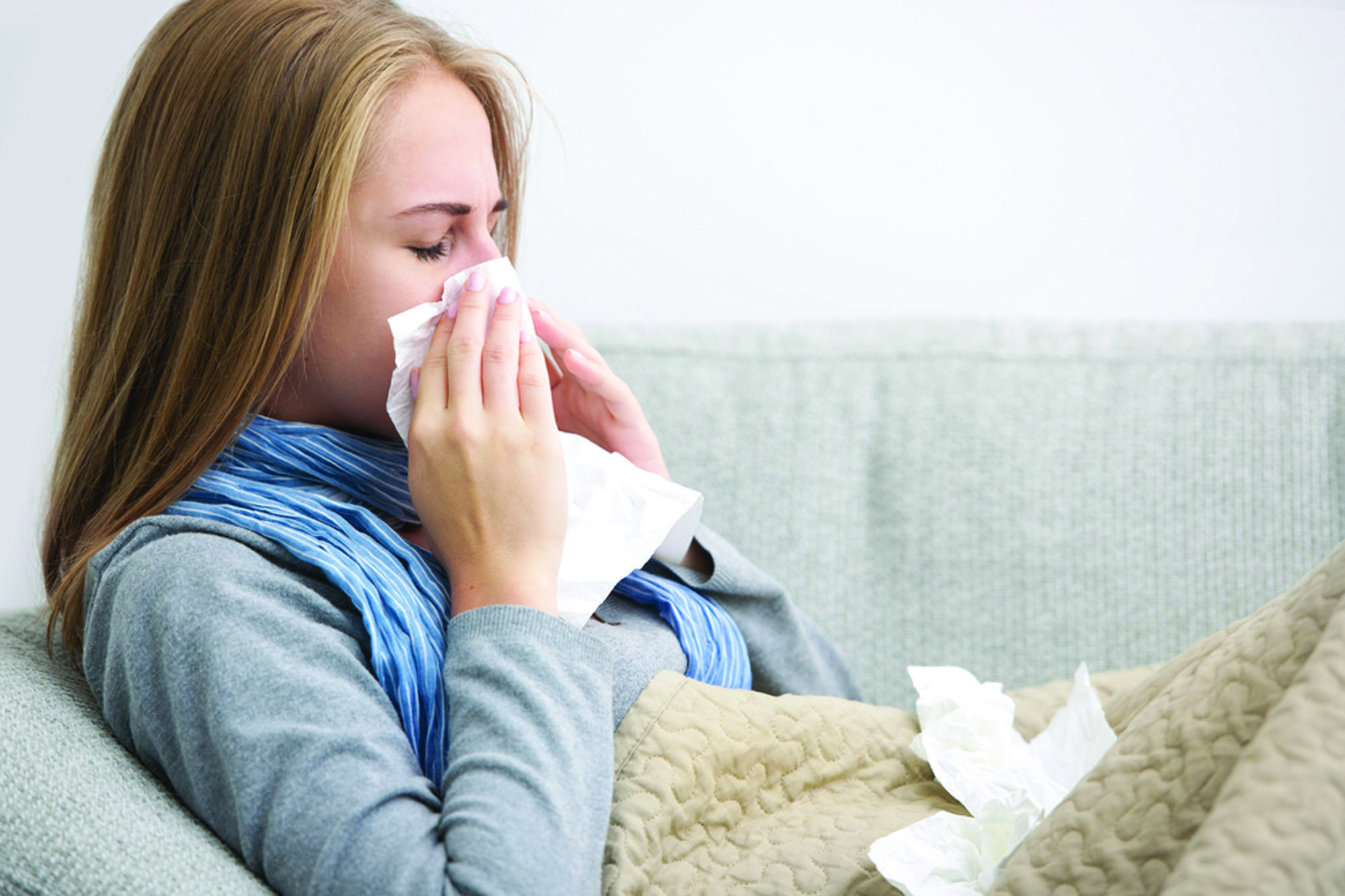 woman on couch sneezing. 